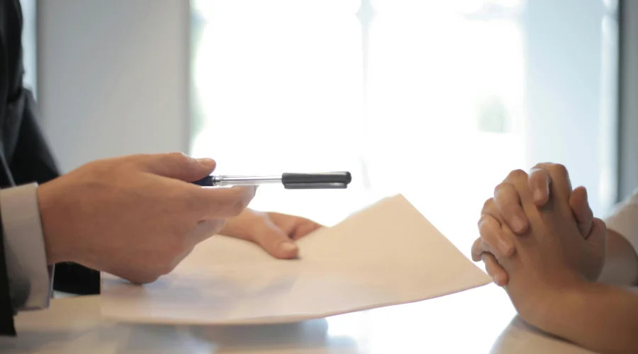 A loan officer handing a pen and paper over to an applicant