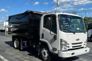 A white dump truck driving on a dirt road