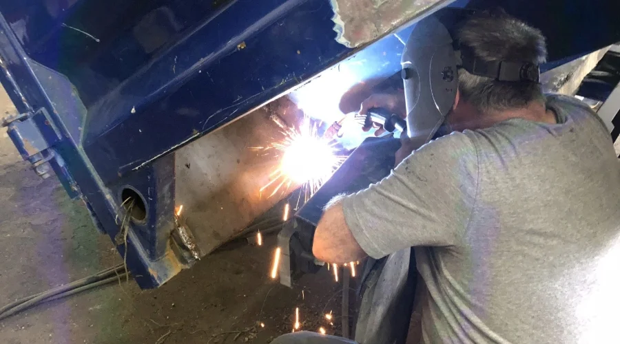 Image of a man welding structural parts of a truck